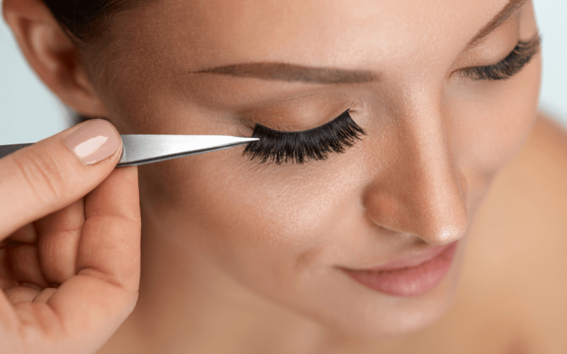 applying false eyelashes to female model's eye