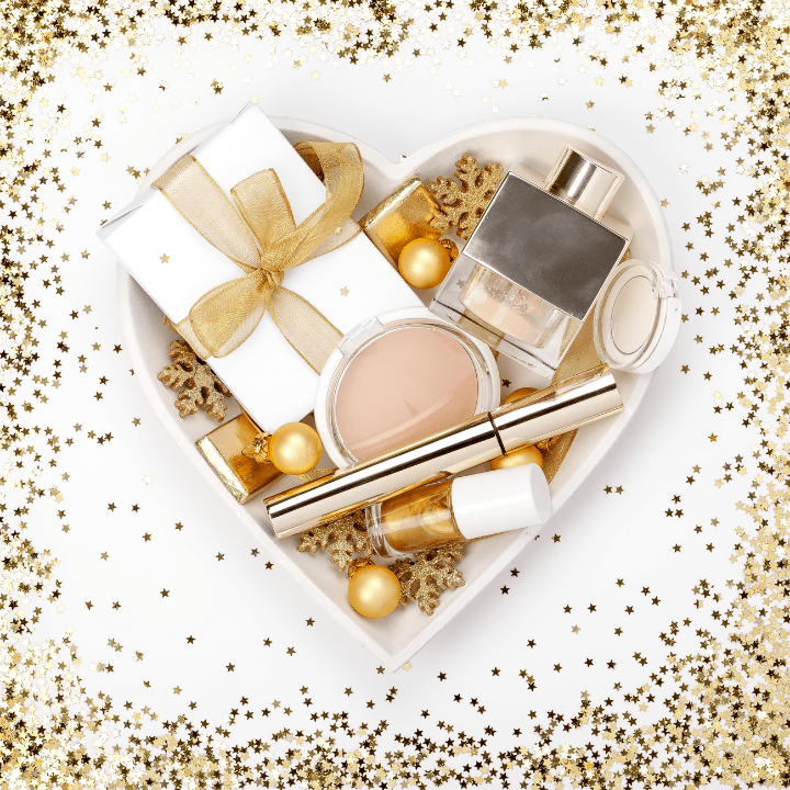 heart-shaped box, surrounded by gold glitter, filled with makeup and beauty presents