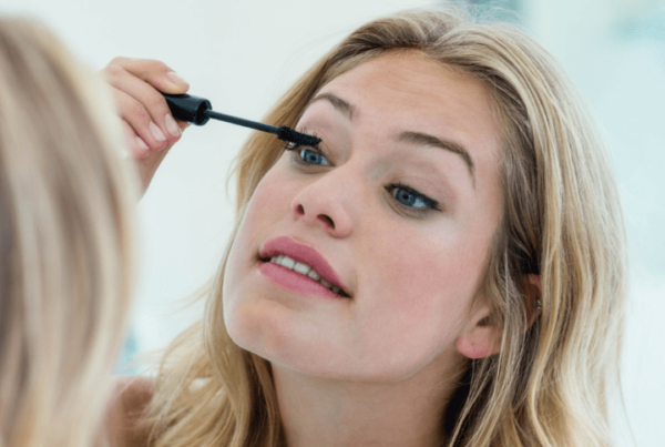 girl applying mascara on herself before attending makeup school