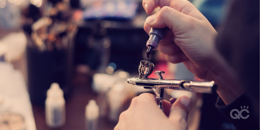 makeup artist putting airbrush makeup into airbrush gun