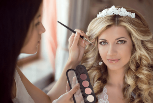 makeup artist equipped with a makeup palette applying makeup on bride