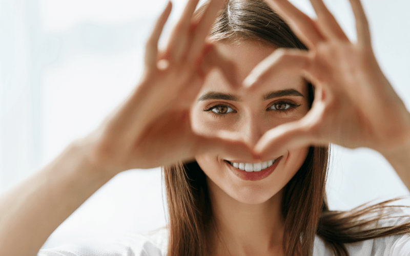 smiling woman making heart symbol with fingers