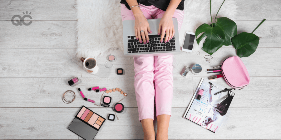 woman writing on laptop, surrounded by makeup and fashion products