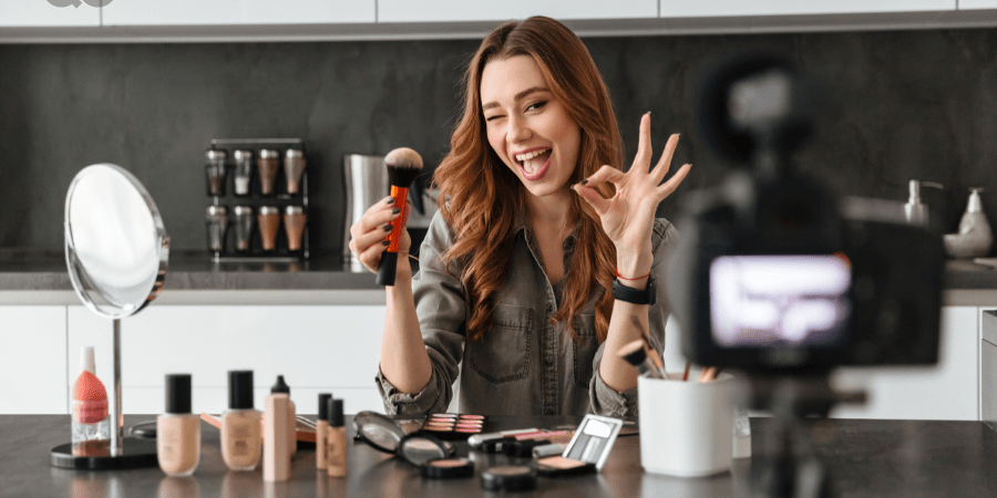 girl with makeup products filming herself doing tutorial