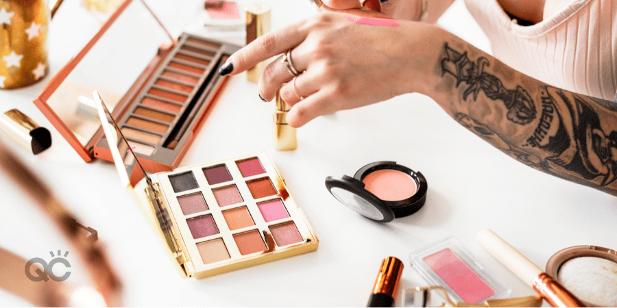 tattooed girl surrounded by cosmetics testing lipstick on hand