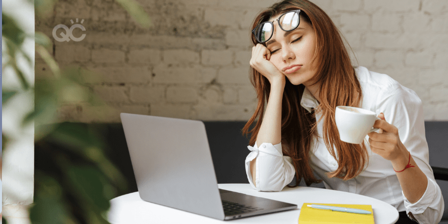 woman holding coffee but asleep at laptop