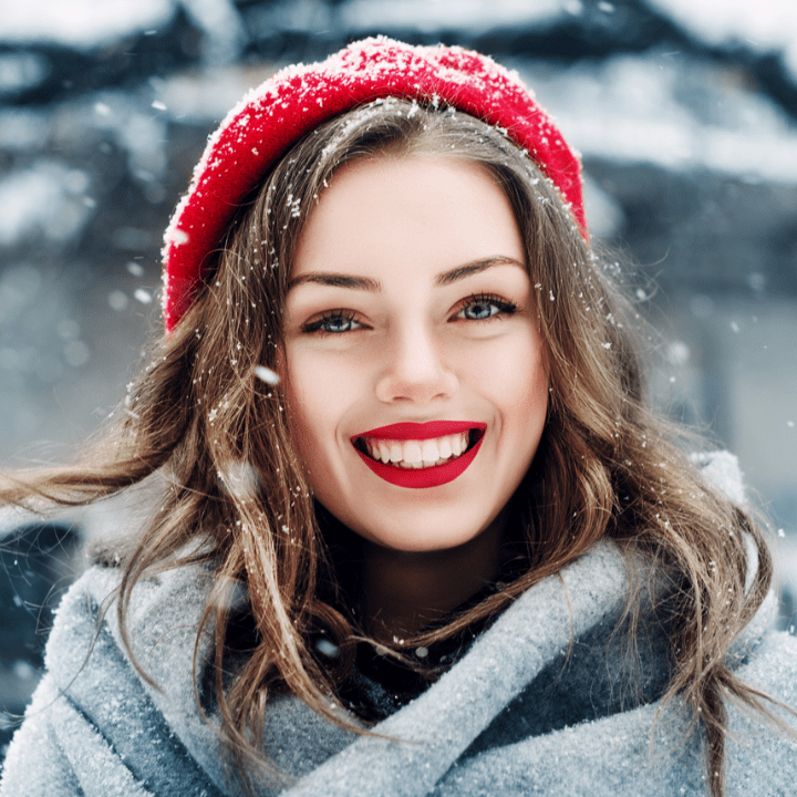 model outside in the snow, with beautiful brows, lashes, and red lip makeup