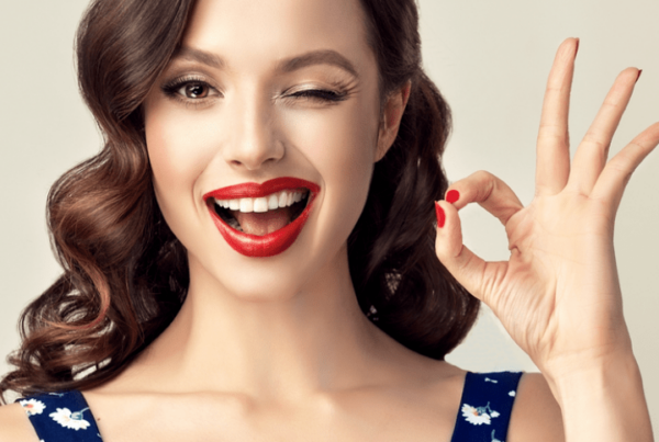 woman with pinup-style hair and makeup winking and giving OK sign with hand