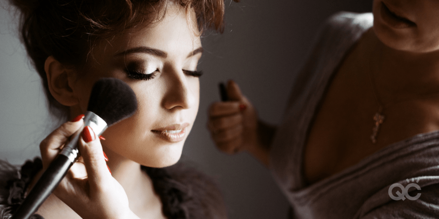 upclose of model's face, with MUA applying powder to cheek with brush