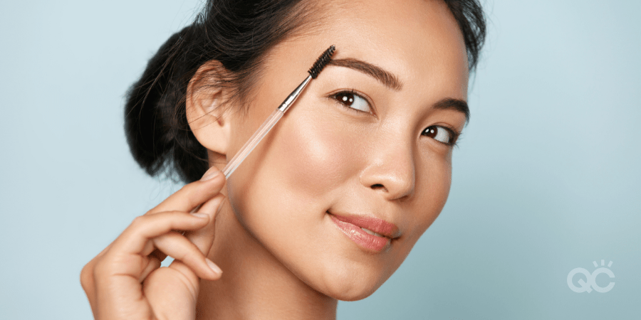 woman brushing eyebrows with a spoolie