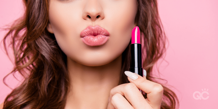 woman making kissing face, while holding up pink lipstick