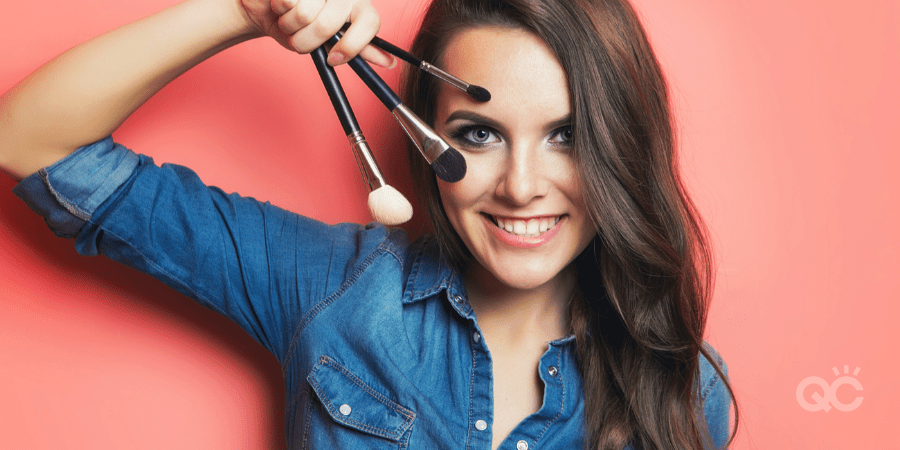 smiling woman holding 3 different makeup brushes