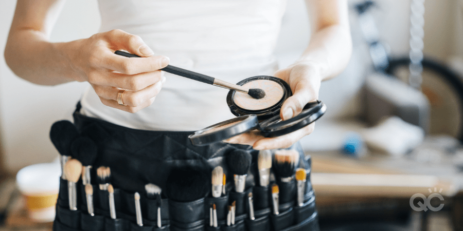 makeup artist wearing smock filled with makeup products/tools