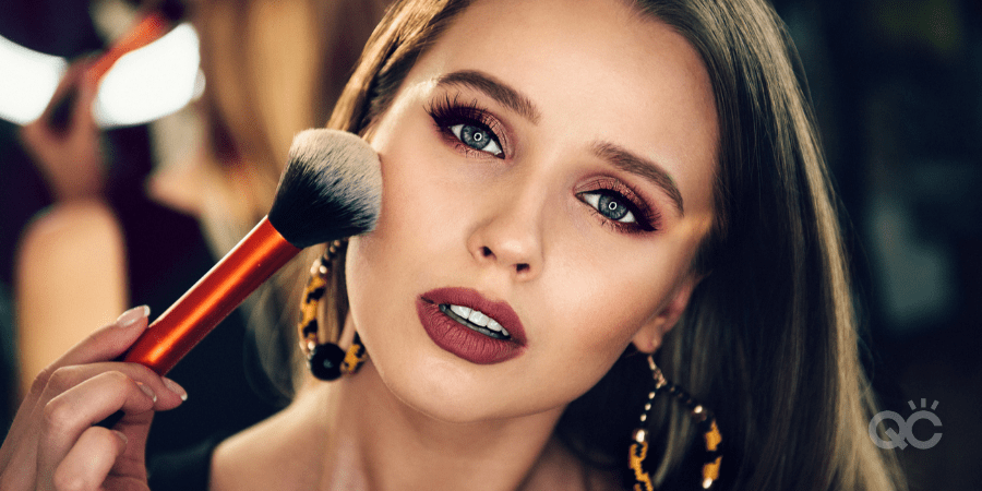 upclose of beautiful woman wearing makeup, brushing powder brush to cheek