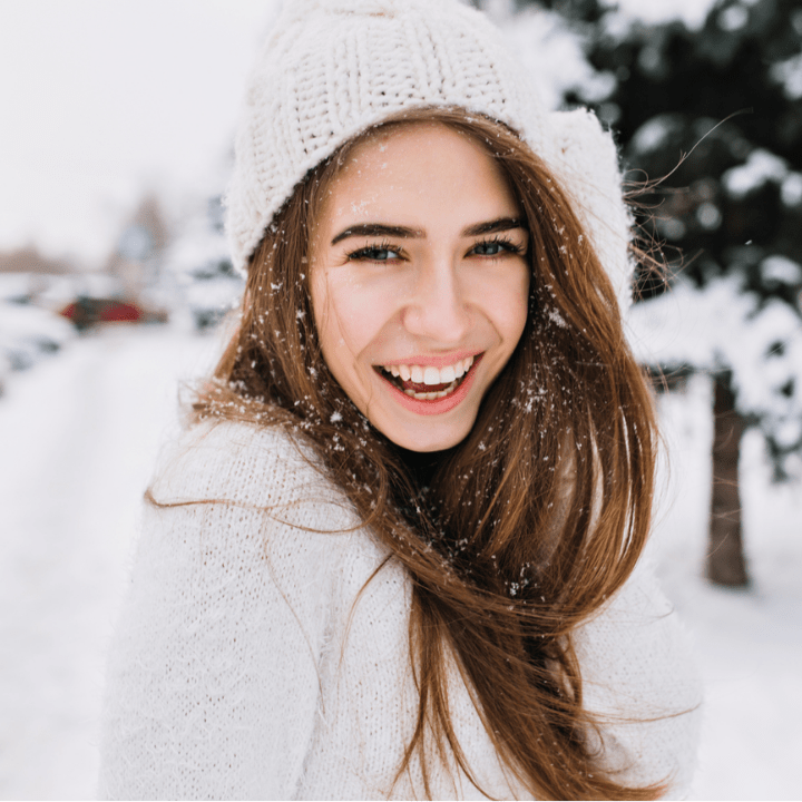 Spectacular long-haired woman laughing while posing on snow background. Outdoor close-up photo of caucasian female model with romantic smile chilling in park in winter day.