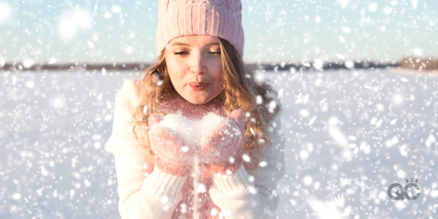 Girl blowing on the snow in the park in winter.