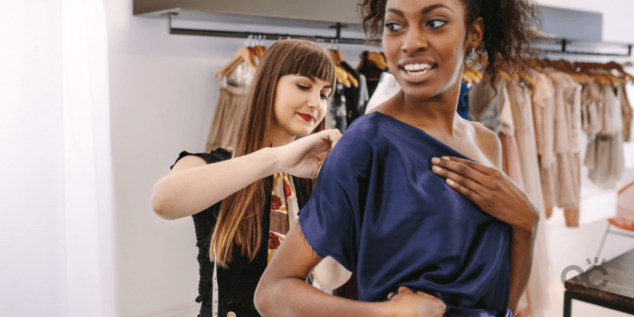 Fashion designer trying new designer clothes on a model. Woman entrepreneur in her cloth shop designing new clothes.