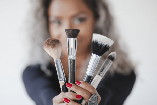 makeup artist holding up makeup brushes