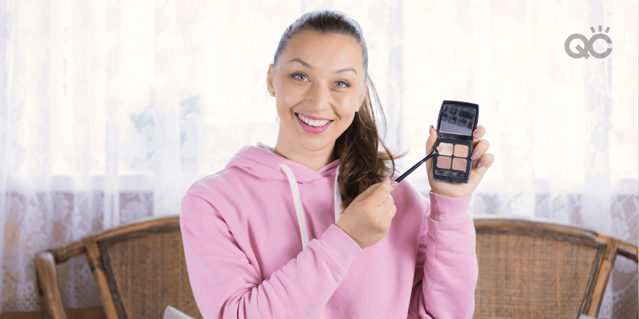 makeup artist looking at camera and holding up eyeshadow palette