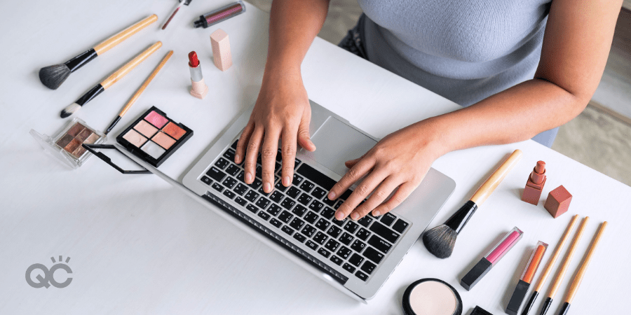 overview of woman typing on laptop, surrounded by makeup products