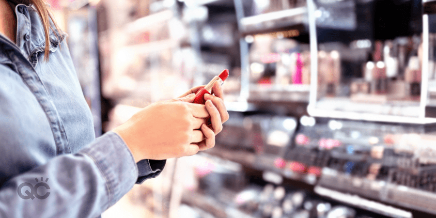 woman holding lipstick in cosmetics section of drugstore