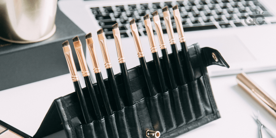 makeup brushes propped up on table in front of laptop