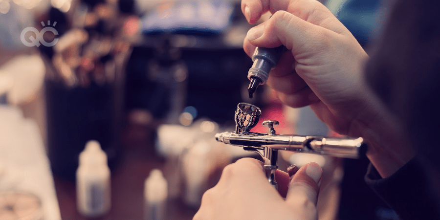 makeup artist putting product into airbrush machine