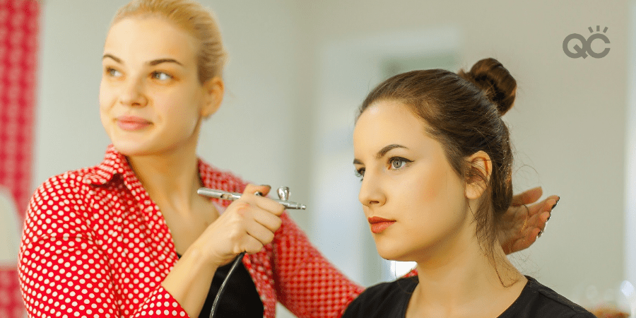 makeup artist using airbrush on client