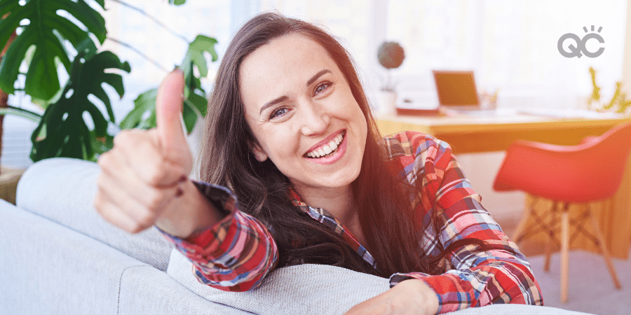 woman sitting on couch, giving thumbs up