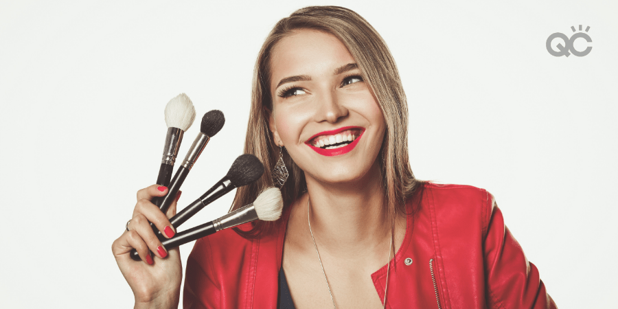 happy woman holding up makeup brushes