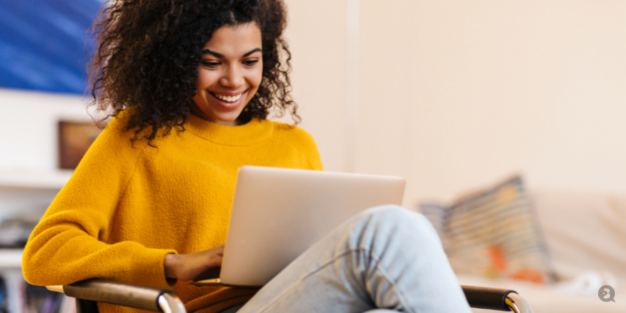 Happy woman on her laptop at home taking QC Makeup Academy course