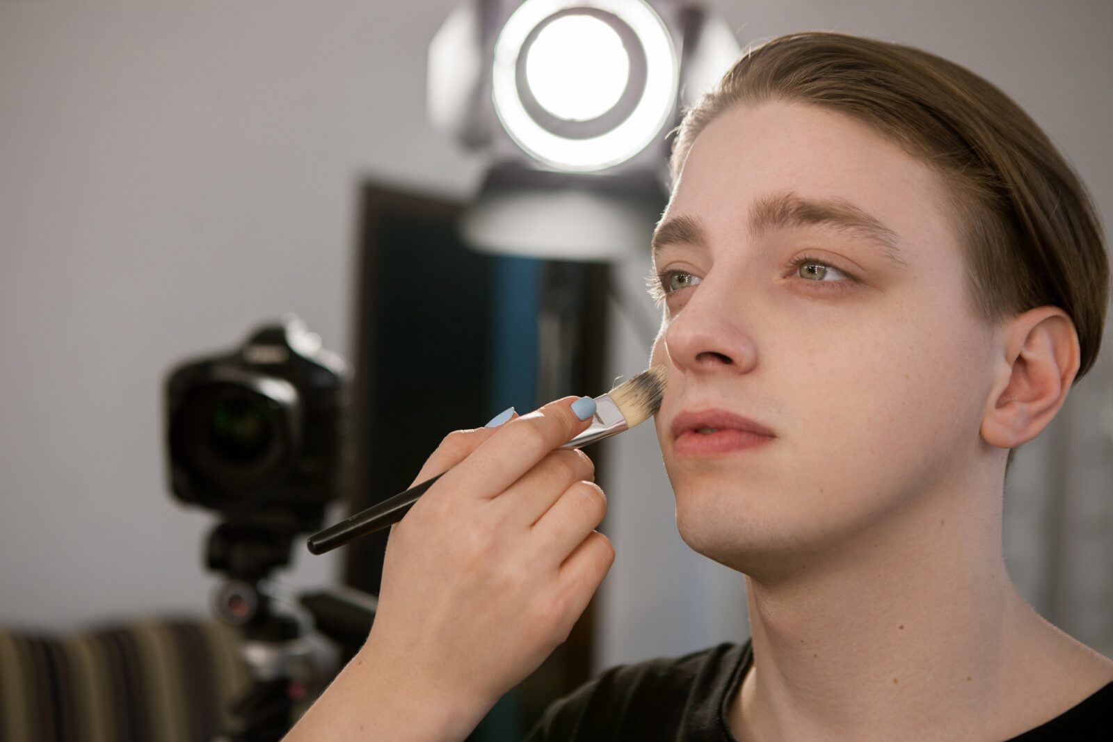 makeup artist putting makeup on male model's face