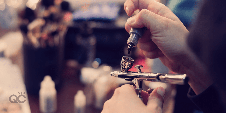 makeup artist pouring product into airbrush makeup machine