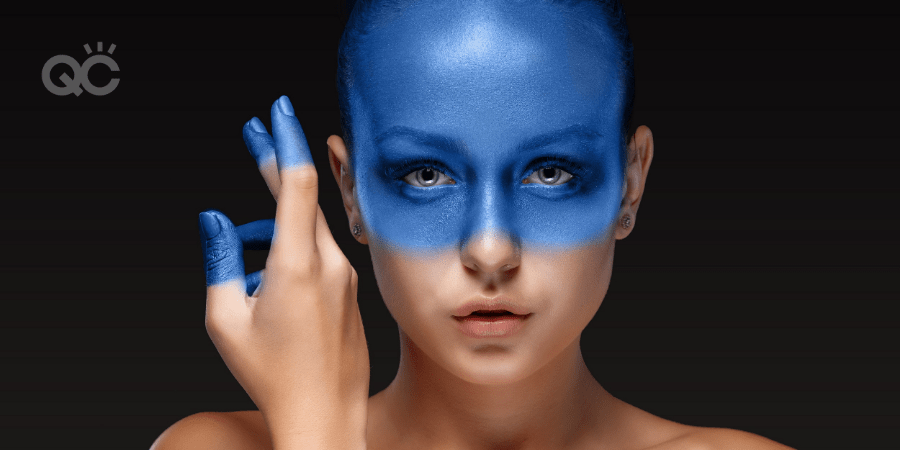 model with bright blue makeup on face and fingertips