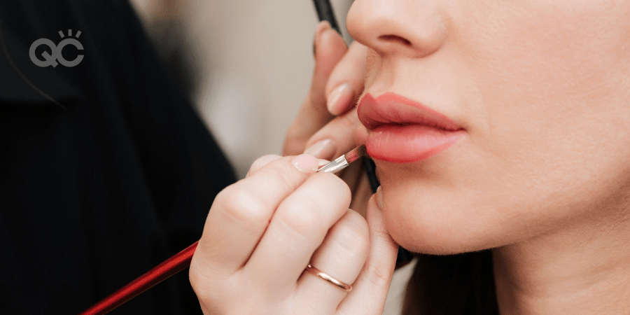 makeup artist applying lip product to model's lips