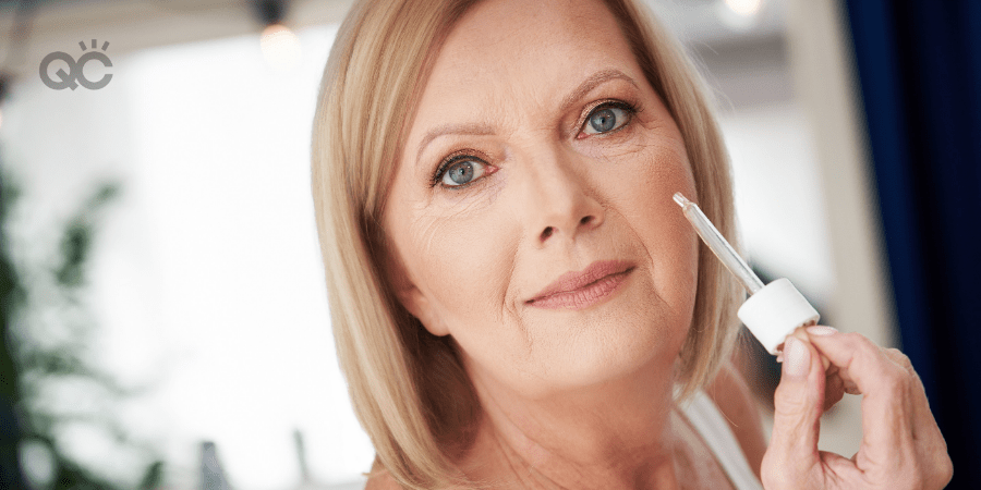 older woman applying skincare serum in cheek