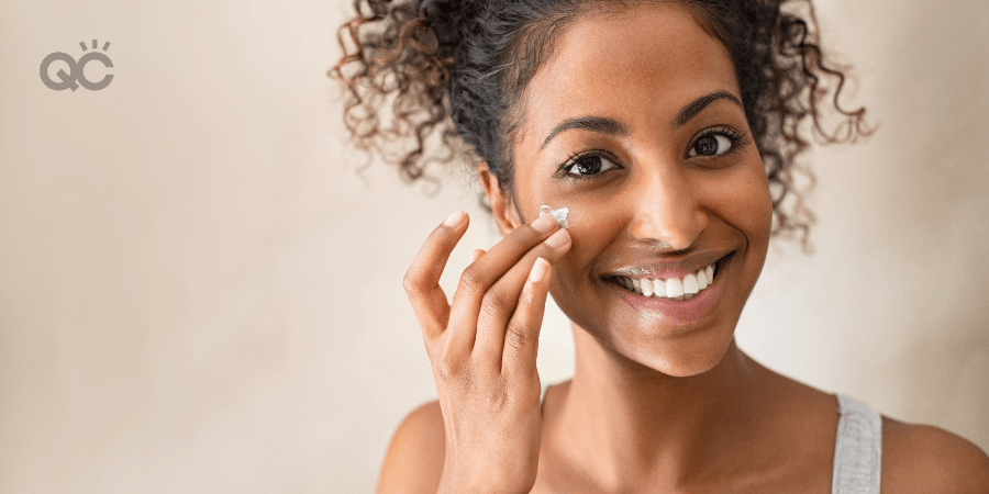 happy woman applying skincare cream to cheek