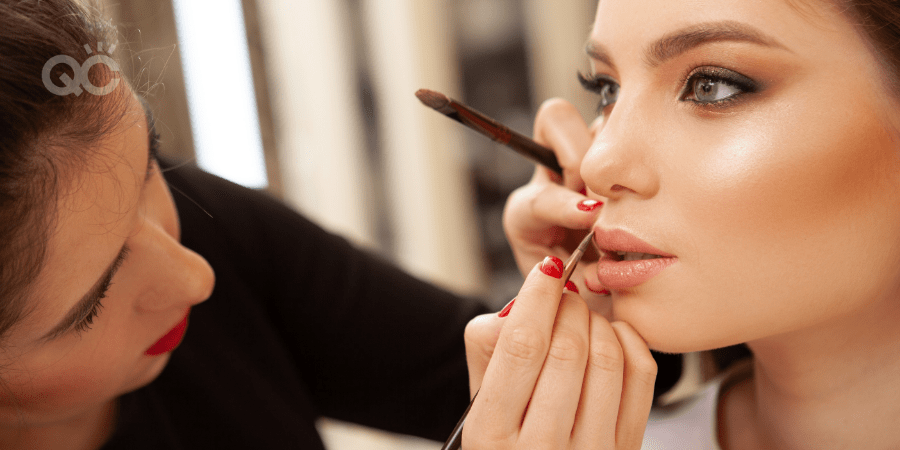 Makeup artist applying lip product on model