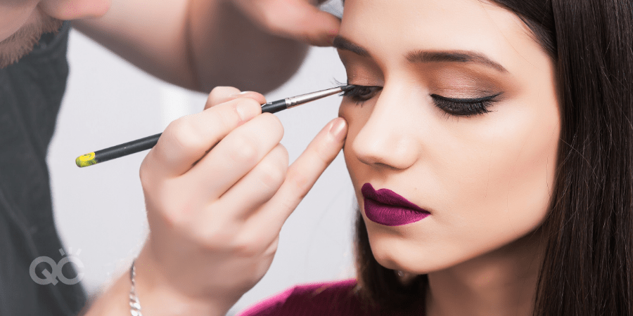 Makeup artist applying eye liner on female client