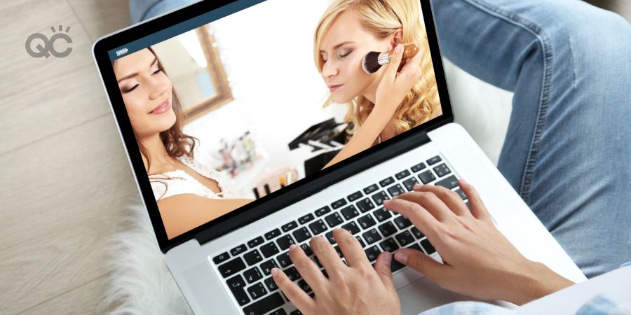 Woman watching makeup tutorial on laptop while sitting on floor