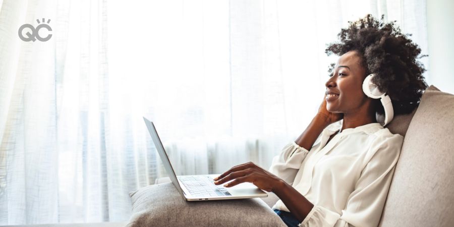 School of makeup in-post image, Shot of a young woman using headphones while relaxing on the sofa at home. Shot of a young woman using a laptop and headphones on the sofa at home