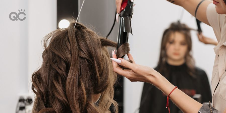 Hair stylist curling client's hair at salon