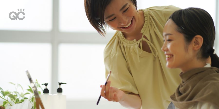 Makeup artist working on happy client, both women smiling