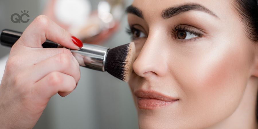 Close up of makeup artist applying light layer of matting powder while using professional brush for lady