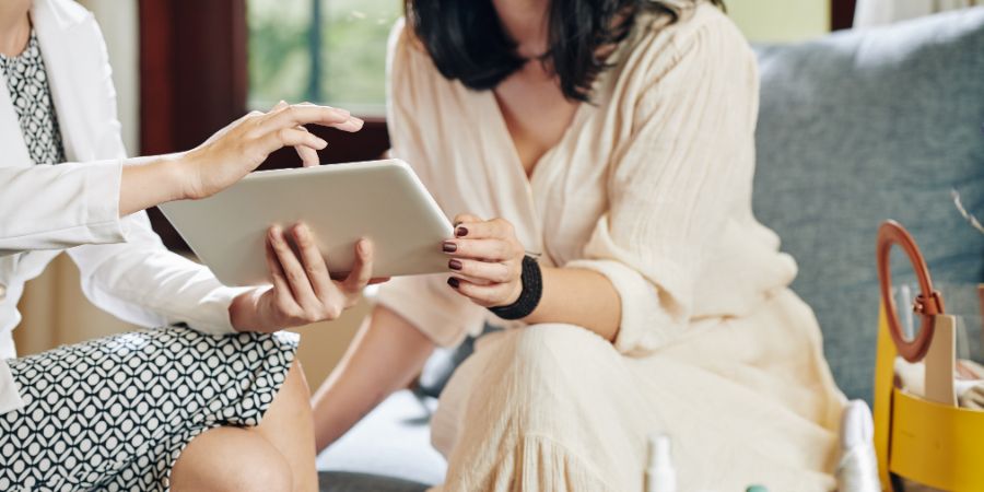 Beautician showing information about new cosmetics and beauty products on tablet computer to client