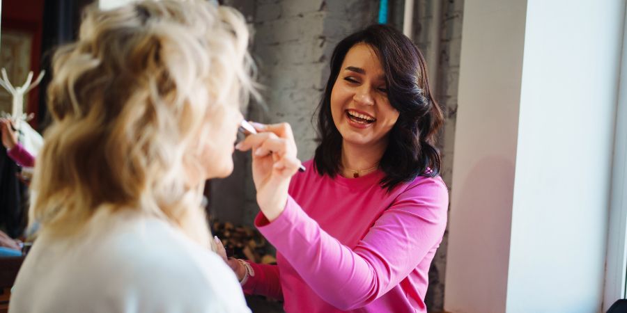 a makeup artist does makeup to a blonde for a holiday or a photo shoot. the concept of professional cosmetic services.