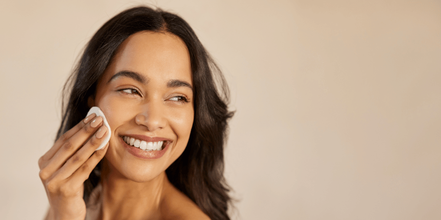 Smiling woman uses makeup remover to remove makeup and give herself a youthful glow