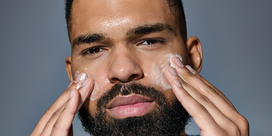 Man applying after shave to shaved areas of face. Man is showing men's shaving aftercare routine.